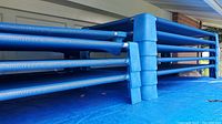Stacked blue daycare cots showing the side profile and blue plastic corner supports.