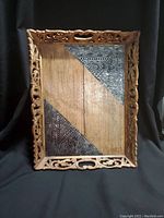Front view of the wooden serving tray showing carved edges and metal inlays on the inside corners.