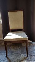 Front view of a dining chair with wooden arms and beige fabric upholstery on seat and backrest.