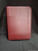 Front cover of one burgundy agenda book showing smooth leather-like texture and brand embossing.