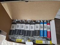 Photo showing all 8 ink cartridges in a cardboard box, sealed in plastic packaging marked 127.