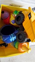 Photo showing a yellow CAT dump truck, colorful stacking rings, blue bucket shaped like Cat Boy character, and other toddler toys piled in a container.