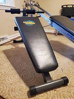 Side angle view of black padded Ultra Toner bench showing cushioned backrest and foam roller foot supports.