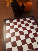 Photo of the wooden chess board with alternating dark and light squares and a dark wood frame.