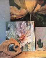 Close-up of smaller white flower painting, natural-colored hollow sculptural piece, and small cactus-shaped green sculpture.