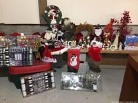 Wide view of assorted Christmas decorations including Santa figures, stockings, wreaths, and ornaments arranged on a shelf and storage bins.