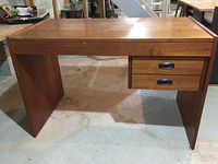 Full view of wooden desk showing flat surface, side panels, and two drawers under right side