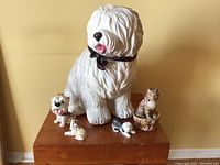 Front view showing six ceramic animal figurines on wooden base against yellow wall.