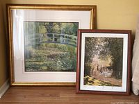 Both framed prints shown together leaning against wall, gold-tone and wooden frames visible.