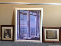 Photo of three framed artworks showing balcony painting in center with sheer curtains and two smaller artworks on sides.