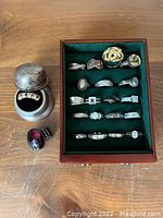 Wooden table with green felt tray holding assorted rings, plus two rings placed on table