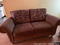 Loveseat with two patterned backrest cushions and solid brown seat cushions shown from front.