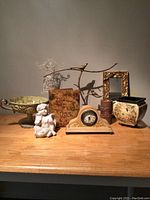 Overview of all decorative items on wooden surface including cherub statue, mantel clock, planter, bowl, photo frame and other pieces.