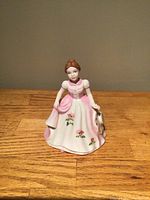 Front view of the Royal Doulton figurine showing lady in pink and white dress with floral details and small dog.