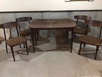 Full view of table and four chairs against concrete wall