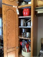 Kitchen cabinet interior showing shelves with cookware, baking dish, and revolving utensils caddy