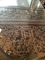 Close-up of carved tabletop scenes under glass