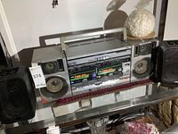 Front view of JVC boom box main unit centered with two detachable speakers on either side