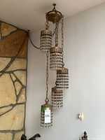 Full view of multi-light fixture hanging against wall next to stone fireplace.