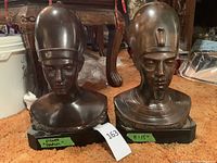 Two Egyptian bust statues side by side on carpeted floor showing overall lot