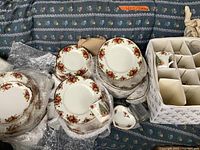 Assortment of stacked dinner and side plates wrapped in bubble wrap with boxed mugs at right