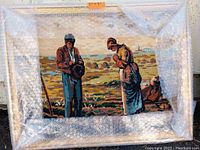 Photo of needlepoint art showing a somber couple outdoors with earthy tones, sized approximately 27 x 21 inches, wrapped partially in bubble wrap.