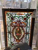 Full view of rectangular stained glass panel with floral design and hanging chains