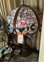 Photo of stained glass lamp with floral shade and lady figure bronze base showing overall design and colors.