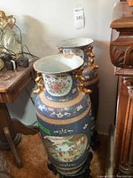 Pair of tall Chinese porcelain vases in blue ground with polychrome enamel and gilt dragon-form handles seated on lacquered wood stands