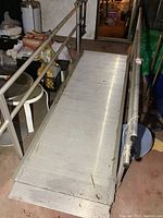 View of aluminum wheelchair ramp showing full length with handrails on both sides and textured surface.