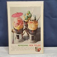 Full view of the Coca Cola advertisement featuring ice cream floats in branded glasses with umbrellas and garnishes.