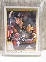Front view of 1991 Mario Lemieux O-Pee-Chee Premier hockey card in black and yellow Penguins uniform inside hard sleeve top loader.