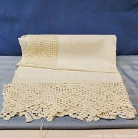 Folded 45-inch square white tablecloth with detailed crocheted lace edge shown on a flat surface