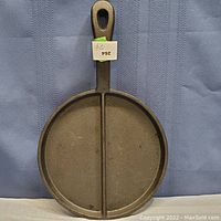 Full view of cast iron divided pan showing the single handle and round divided base.