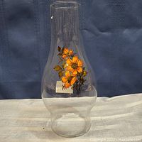 Full view of translucent glass oil lamp chimney showing overall shape and floral decoration.