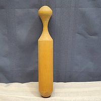 Full view of the wooden masher showing cylindrical body with rounded bottom and tapered handle with knob end