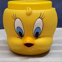 Front and close-up view of the yellow ceramic cup shaped like Tweety Bird's head with detailed facial features.