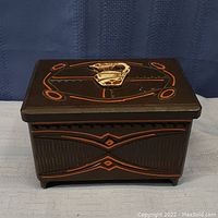 Top view of the closed wooden music box showing decorative orange and light inlay design on the lid and sides.