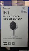 Front of the original box showing Arenti IN1 branding and camera image. Details include full HD 1080P resolution and compatibility with Amazon Alexa and Google Assistant. SD card included label visible.