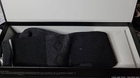 Folded black and grey heated socks inside original packaging box showing knit fabric and ribbed cuff.