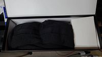 Pair of folded black heated socks inside a white and black box, with a smaller white box next to the socks possibly containing batteries or charger.