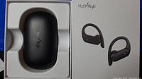 Box and packaging showing black charging case with Holy High branding and image of sport earbuds with ear hooks on box cover.