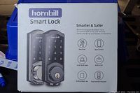 Box front showing the Hornbill Smart Lock image and main features: key free, app control, anti-theft alert, auto lock, battery back-up, touchscreen keypad.