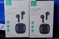 Two boxed packs of black USAMS IA Series True Wireless Stereo earbuds with charging cases shown on front of packaging.