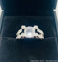 Front view of the ladies 925 silver ring with 2 carat main cubic zirconia stone and smaller accent stones on split band, in a black velvet ring box.