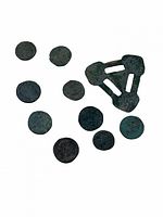 Photo showing 10 dark patina round coins and 1 triangular metal artifact with three cutout bars, all with a greenish patina indicating age.