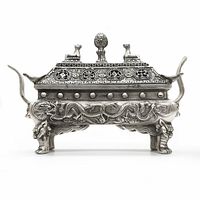 Front view of Tibetan silver two-piece incense burner showing dragon motifs, Foo dog finials, and feet with handles.