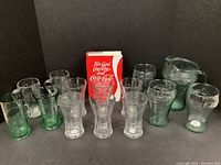 Full collection including six Coca-Cola glasses, two green mugs, a pitcher, and the book.
