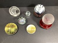 Full set of seven glass paperweights including two globes with stands and various decorative designs.