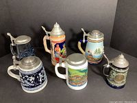 Group photo showing six varied German beer steins with pewter lids.